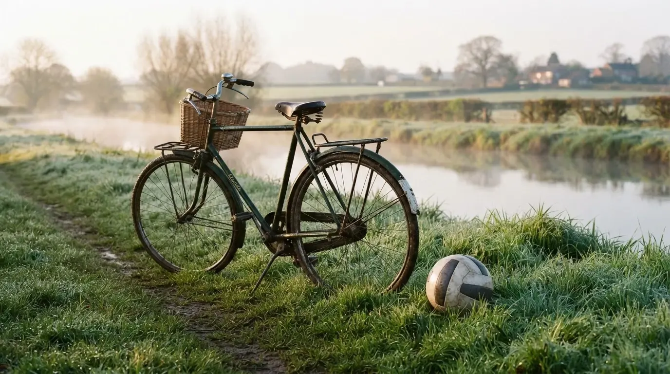 Ein Fussball liegt auf einer Wiese neben einem Fahrrad, im Hintergrund ein Kanal im Morgenlicht