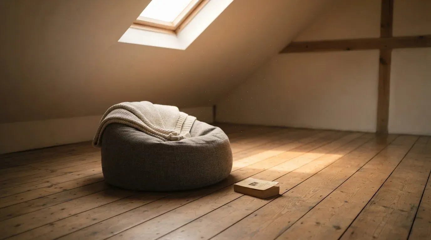 Ein leerer Sitzsack steht in einem Zimmer mit Dachfenster, Abendlicht fällt auf den Holzboden