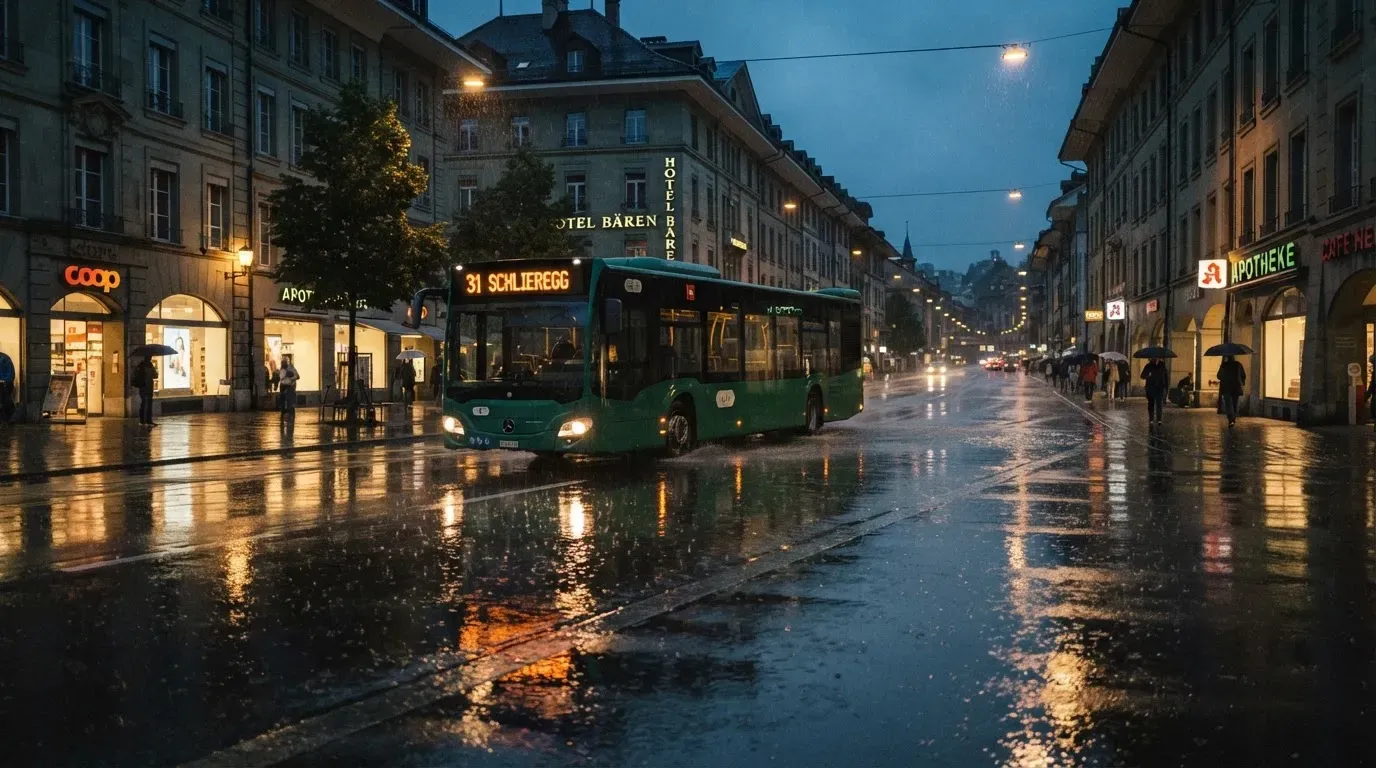 Ein Stadtbus fährt an einem regnerischen Abend durch eine Strasse mit Pfützen, die Lichter spiegeln sich im Asphalt.