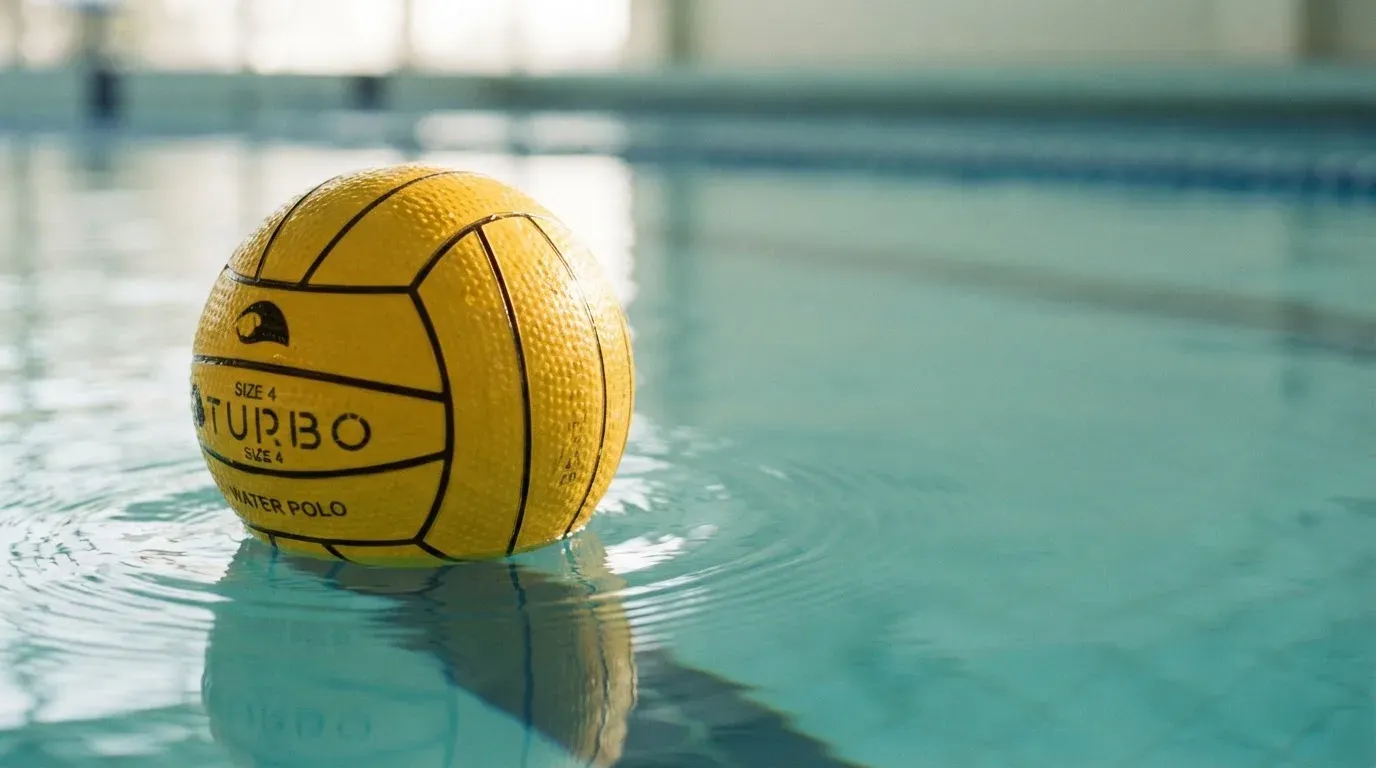 Ein gelber Ball treibt auf ruhigem türkisfarbenem Beckenwasser, feine Wellen im weichen Licht.
