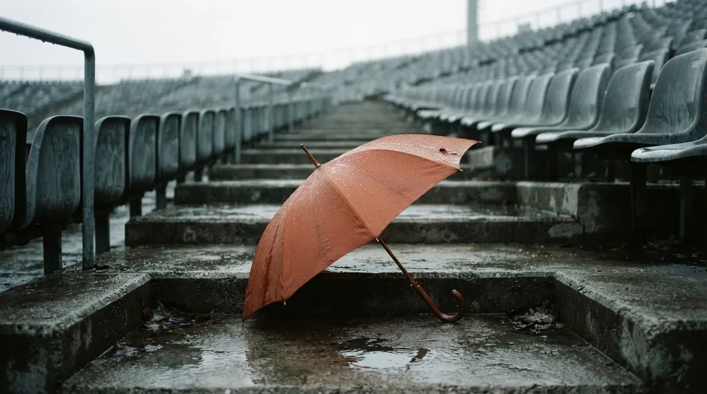 Ein Regenschirm liegt auf einer nassen Treppe zwischen leeren Zuschauerrängen.